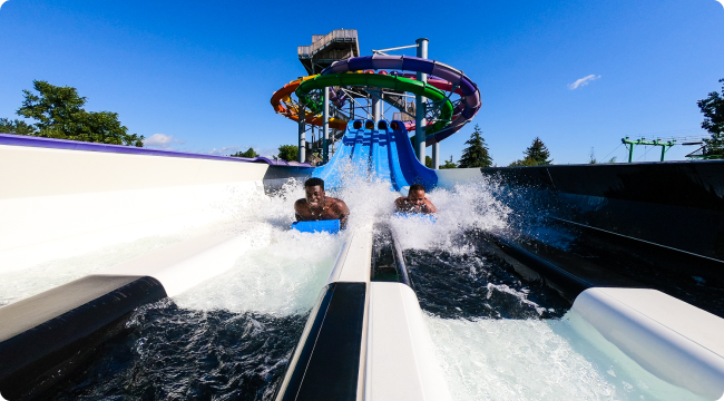 Two guys riding down a water slide