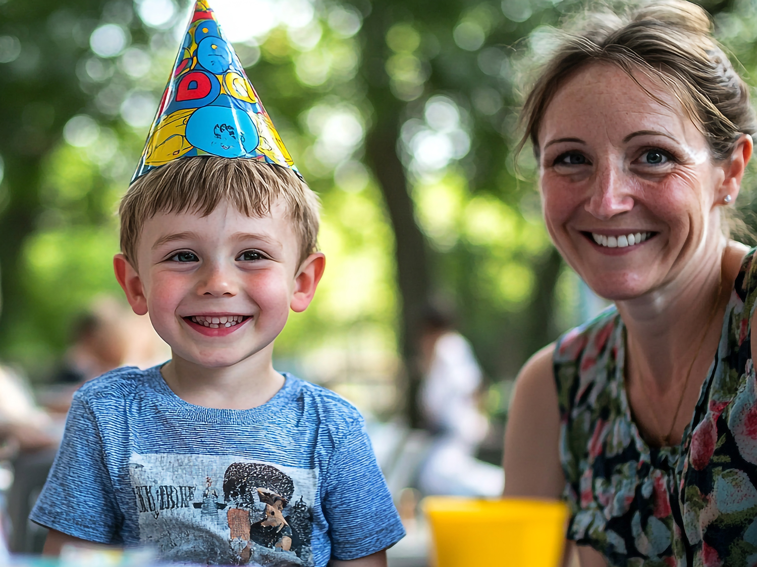 A joyful child wearing a party hat at a summer birthday celebrat